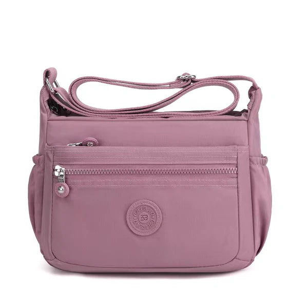 Lightweight nylon crossbody bag in Pink – water-resistant, 4 zip sections and wide adjustable strap