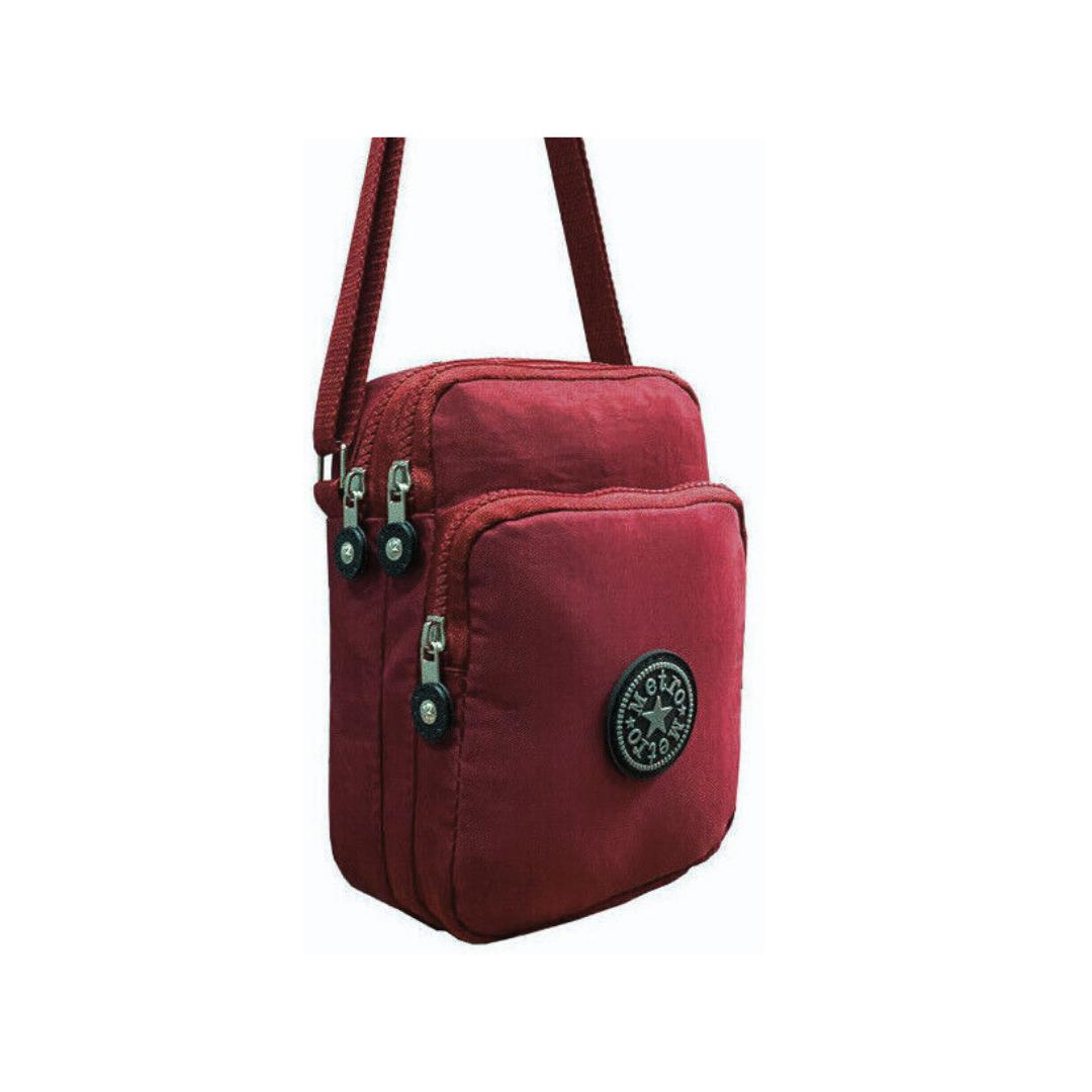 A small red nylon crossbody bag with a front zippered pocket, a top zippered compartment, logo patch on the front, shown on a plain white background.