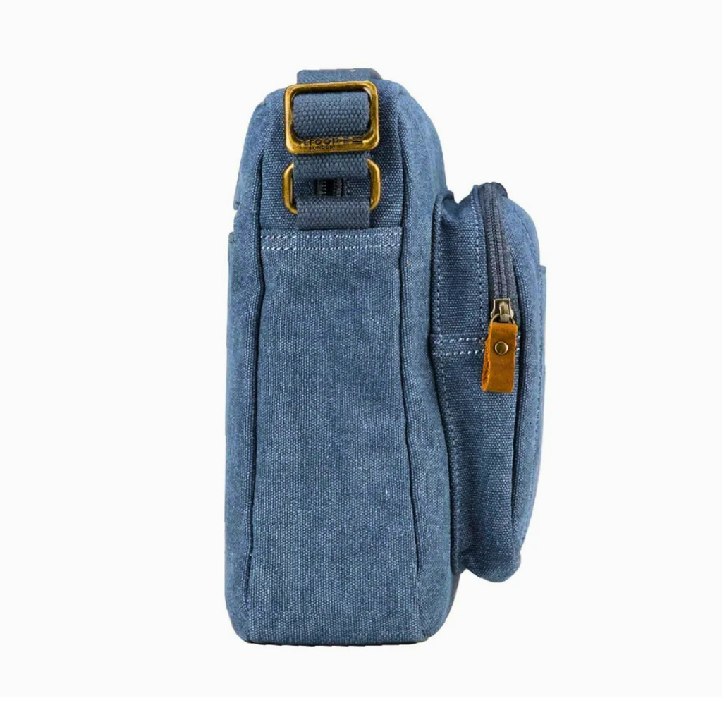 Blue side view of Troop London Large Canvas Cross-body Bag - A4 Size & Brass Hardware with an adjustable shoulder strap, front pocket, shown against a plain white background.